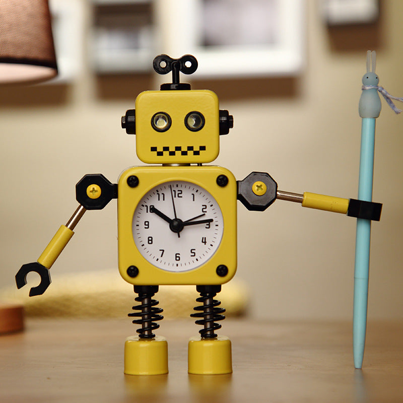 Sveglia-robot gialla in stile cartoon, corpo a orologio con braccia e gambe a molle, porta una matita blu.