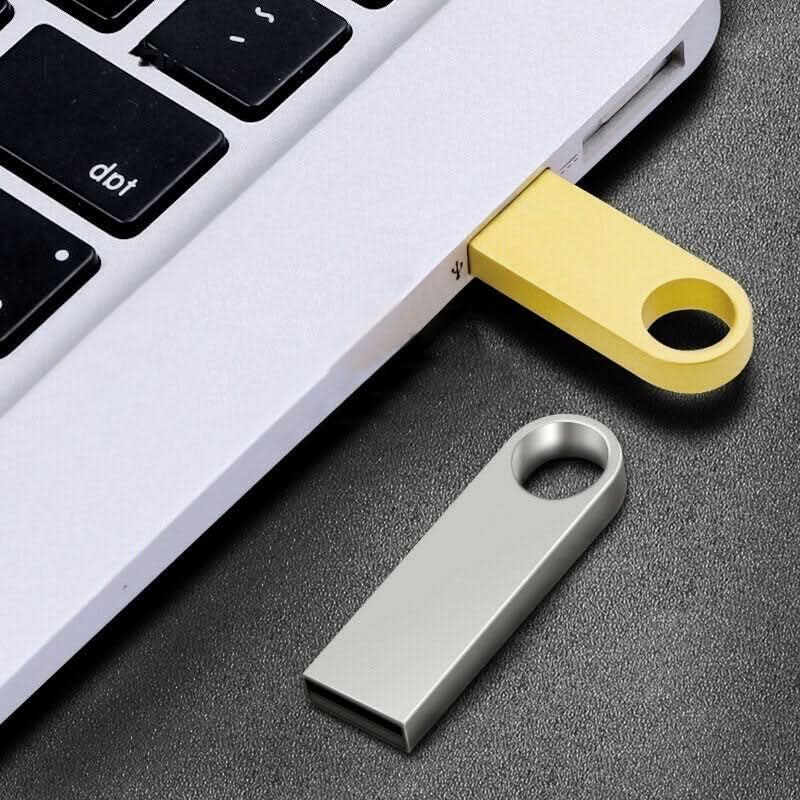 Due chiavette USB metalliche, grigia e gialla, accanto a laptop.