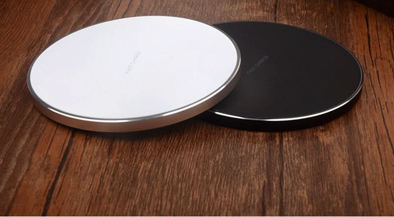 Due basi di ricarica wireless rotonde bianche e nere, ricarica rapida per smartphone su tavola di legno.