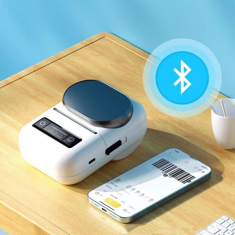 Mini stampante termica per etichette portatile in plastica bianca, USB e Bluetooth, accanto a smartphone con barcode.