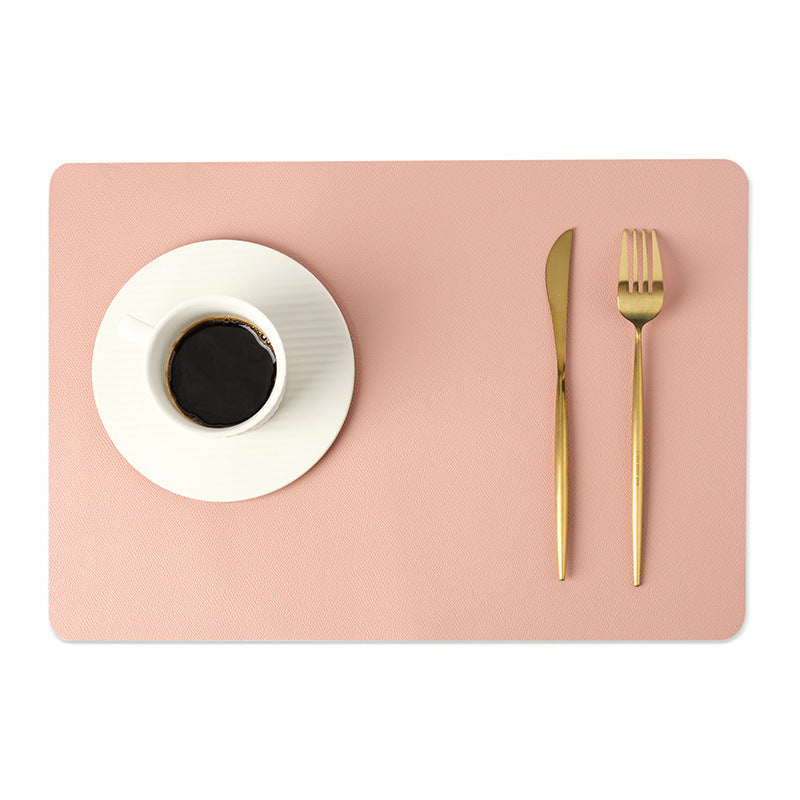 Sottopiatto in ecopelle a tinta unita rosa pesca, resistente al calore e agli oli, con tazza e posate dorate.