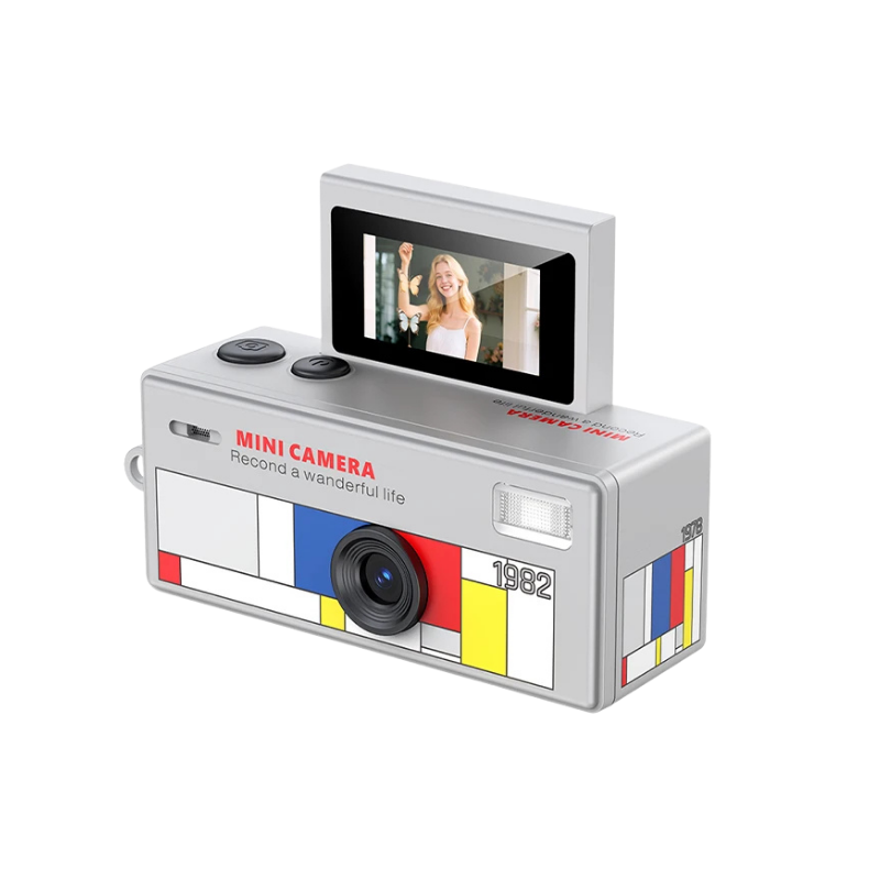 Mini camera digitale silverata retro con schermo flip 180°, design geometrico colorato e lente HD per foto e video.