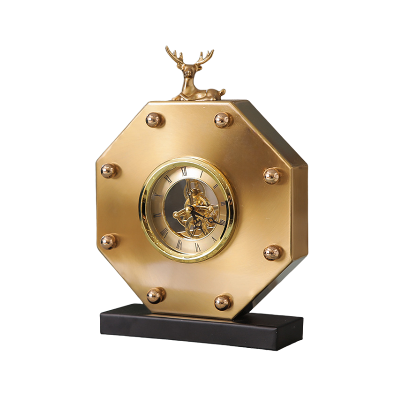 Orologio da tavolo ottagonale dorato con movimento scheletrato, cervo decorativo sulla sommità e base nera.