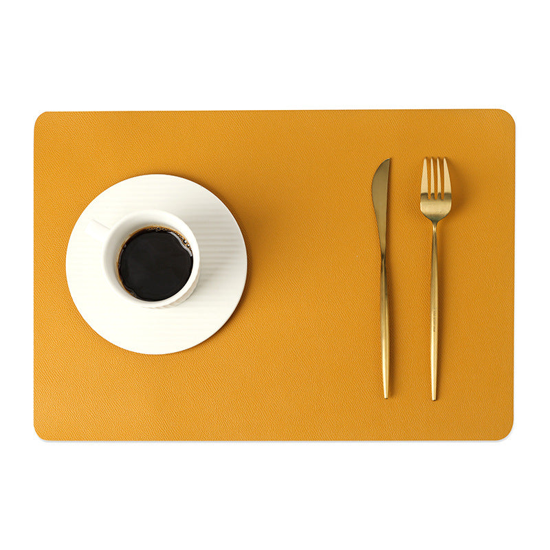 Sottopiatto in ecopelle senape con tazza di caffè bianca e posate dorate