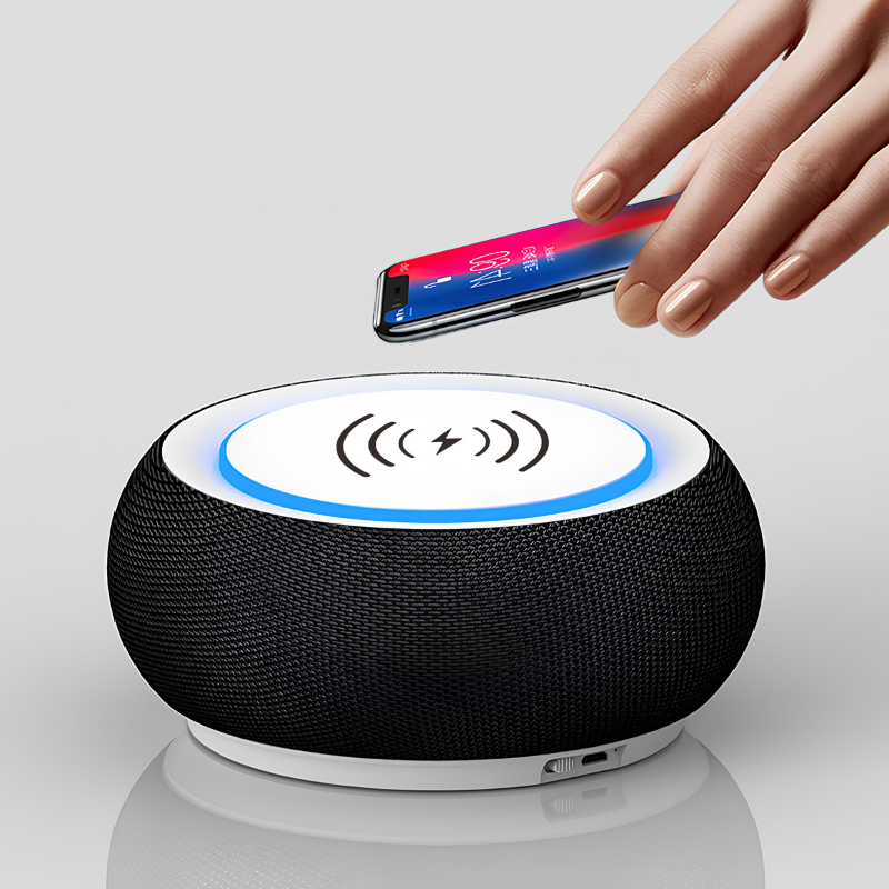 Altoparlante Bluetooth rotondo con superficie di ricarica wireless, anello LED blu e telefono appoggiato sopra.
