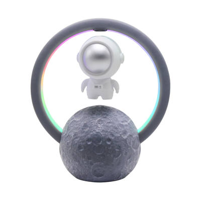 Speaker Bluetooth con astronauta levitante dentro cerchio LED, su luna decorativa.