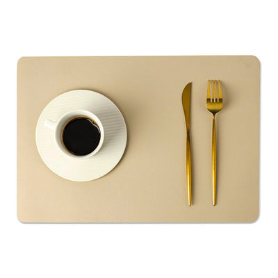 Tovaglietta in ecopelle tinta unita beige con tazza di caffè e posate dorate.