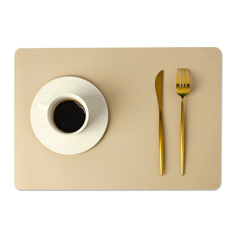 Tovaglietta in ecopelle tinta unita beige con tazza di caffè e posate dorate.